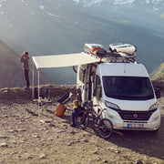 Camper van parked in a mountainous area with people around
