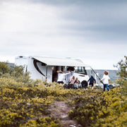 The closed, sleek black and white cassette housing attached to the side of a white motorhome, which contains the rolled-up awning fabric.